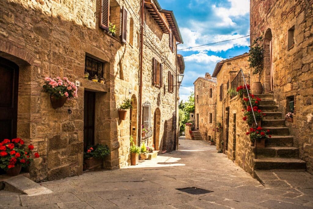 Vicolo di un borgo in pietra con scalinate e vasi di gerani fioriti