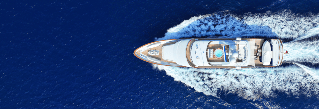Uno yacht in navigazione visto dall'alto, con la scia bianca sul mare blu