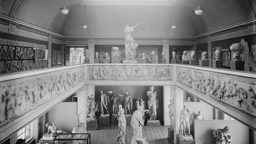 Foto in bianco e nero di una galleria di museo con statue classiche e fregi