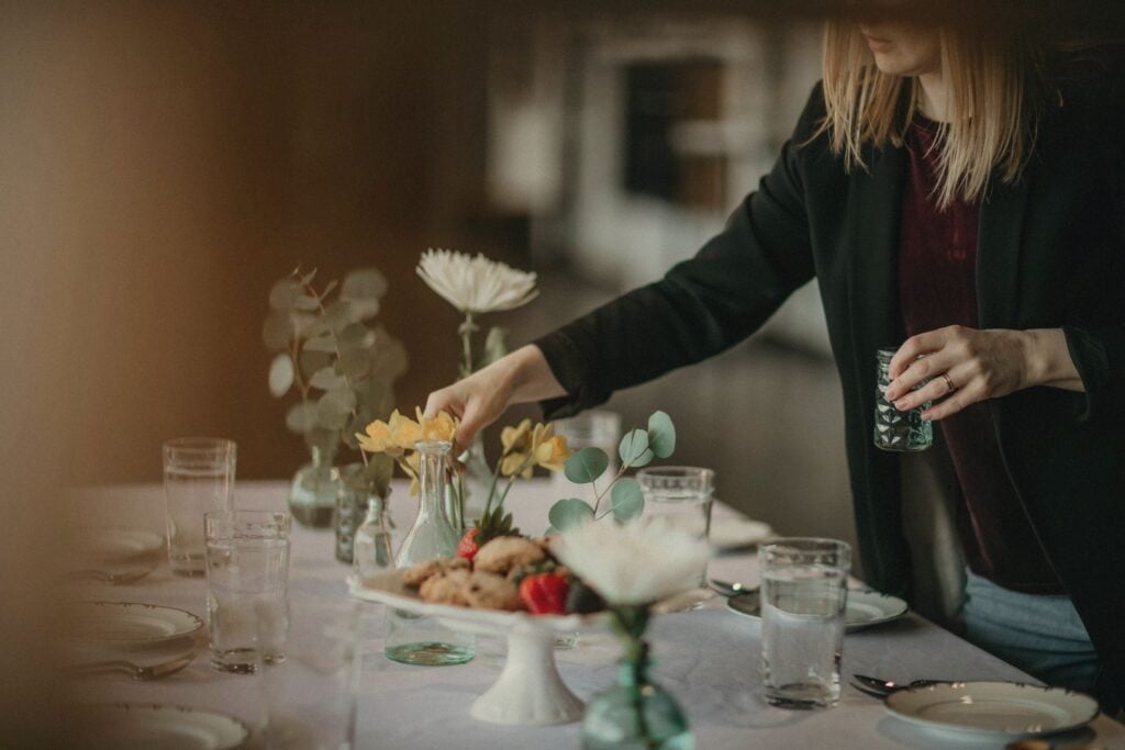 Una wedding planner sistema i fiori sulla tavola di un ricevimento