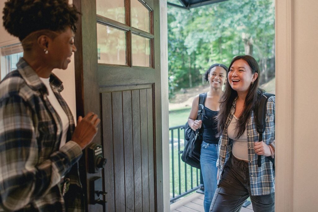 Una host apre la porta di casa e accoglie due ospiti in arrivo