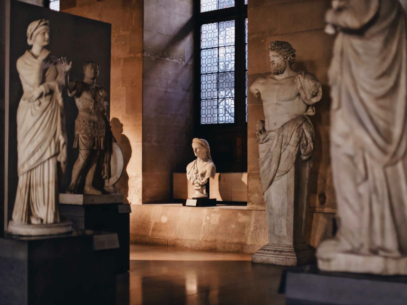 Statue classiche e un busto di marmo nella sala di un museo, nella luce di una finestra
