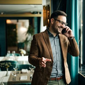 Portrait of a smiling businessman in restaurant talking on smart phone.