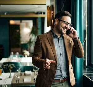 Portrait of a smiling businessman in restaurant talking on smart phone.